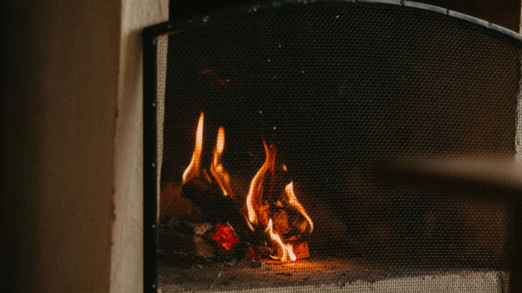 Pare-feu cheminée devant un foyer ouvert avec flammes et grille pare-étincelles